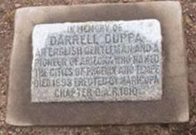 A snapshot of a marker set into concrete that reads, "In memory of Darrell Duppa / An English gentleman and a pioneer of Arizona who named the cities of Phoenix and Tempe. / Died 1898. Erected by Maricopa Chapter D.A.R. 1910."