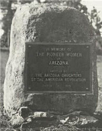 A snapshot of an historical plaque mounted on an upright stone; indistinct wording includes “In Memory of the Pioneer Women of Arizona; Erected by The Arizona Daughters of the American Revolution”