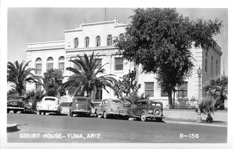 A postcard photograph of the Yuma County Courthouse with a well-grown elm tree.