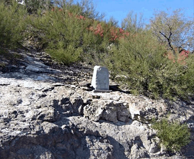 A snapshot of an upright stone marker on a rocky promontory in the mid-ground.