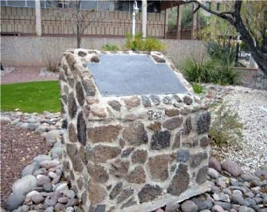 A snapshot of a concrete and stone marker base with a plaque situated in river rock. Marker text is in the body of this page.