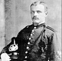 A studio photographic portrait of Will C. Barnes in uniform, holding his hat.