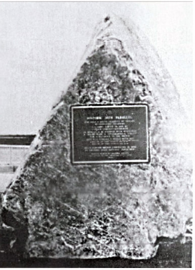 A vintage snapshot, quite blurry, of a large pyramid-shaped stone with an unreadable plaque. Marker text is in the body of this page.