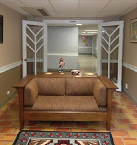 A snapshot of a room interior with open doors, a small sofa, a sofa table with Arizona artifacts, and the edge of a hand-woven Navajo-style rug.