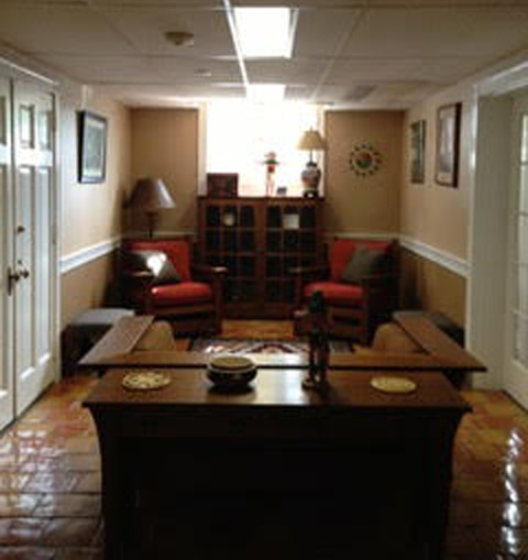 A snapshot of the same interior taken from behind the sofa. A cabinet, lamp, and two chairs are visible.