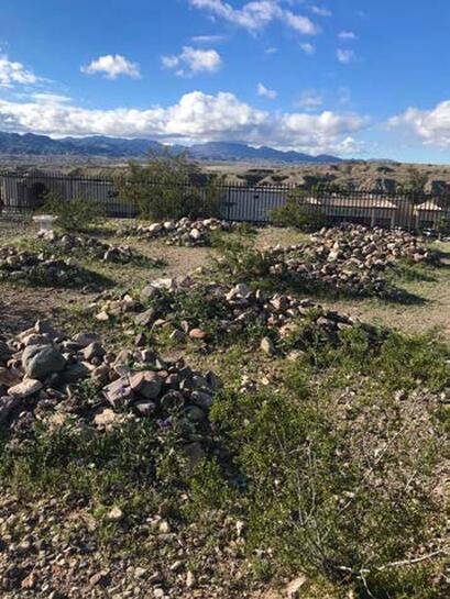 A snapshot of two rows of graves, each covered by a mound of rocks.