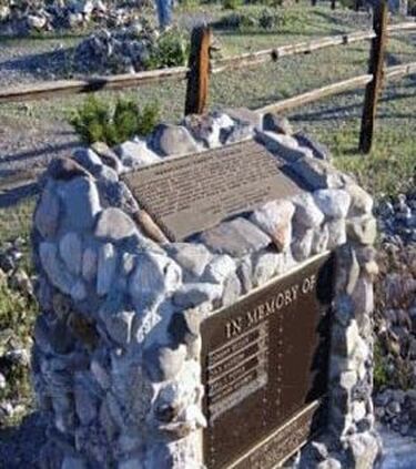 A snapshot of a concrete and stone marker with a plaque on top; plaque text is in the body of this page. A second plaque on the front reads, “In Memory of,” and has room for names to be added..