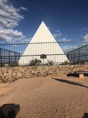 A snapshot of a white pyramid in a fenced area.