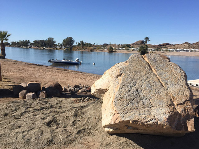 A snapshot of the boulder in place with water and hills in the background.