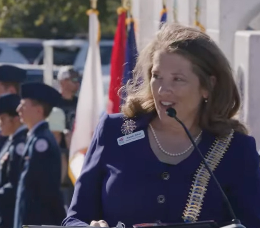 A snapshot of Sarah Ziker speaking at a podium.