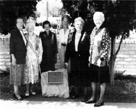 A blurry snapshot of six women standing around a stone marker.